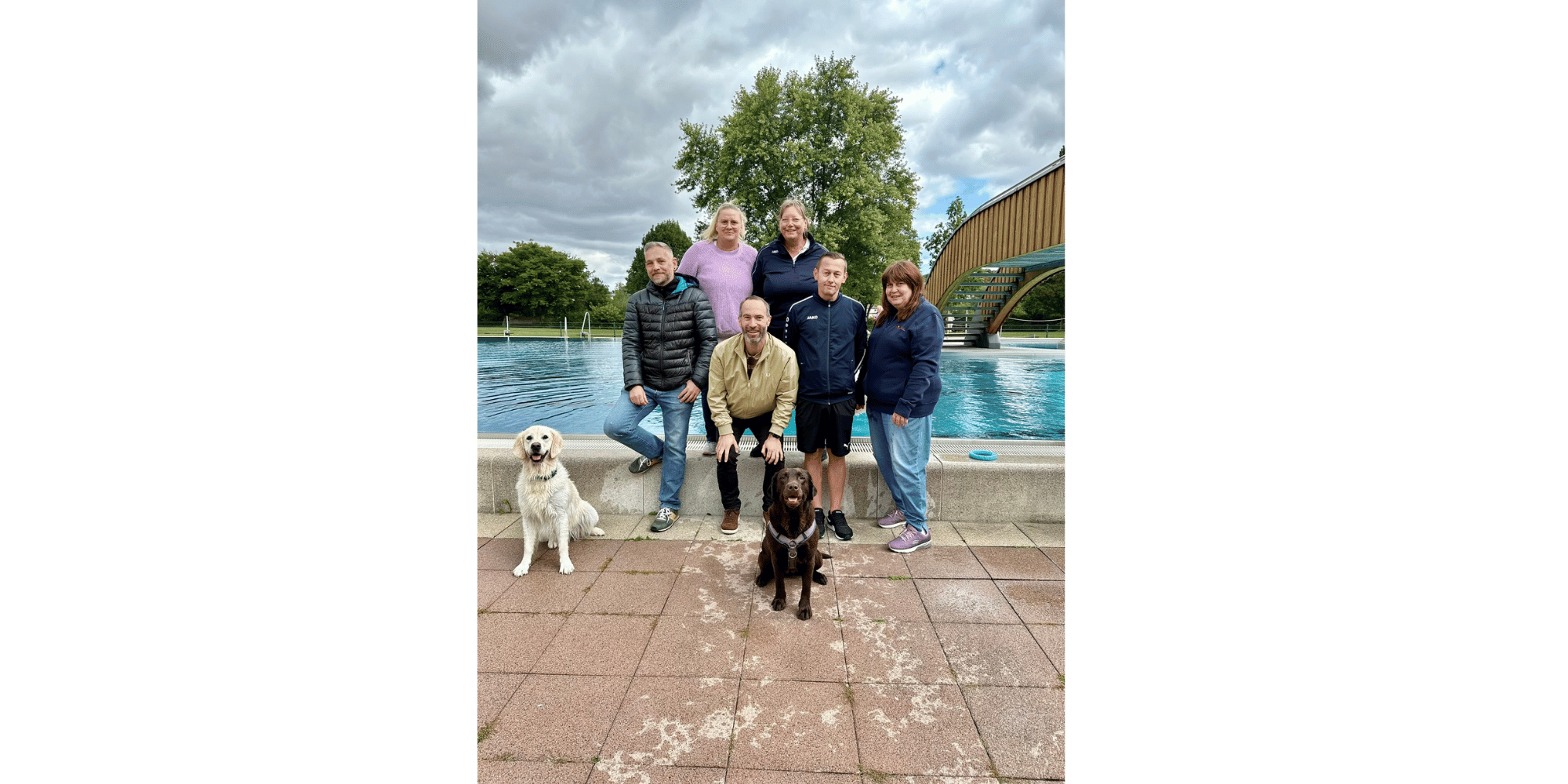 6 Personen und 2 Hunde vor einem Schwimmbecken