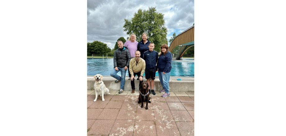 6 Personen und 2 Hunde vor einem Schwimmbecken