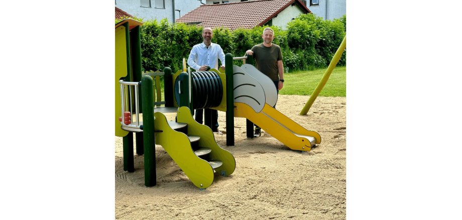 Zwei Männer stehend hinter einem Kleinkinder-Spielplatz