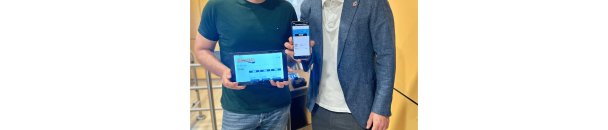 Zwei Männer stehend mit einem Tablet und einem Handy in der Hand