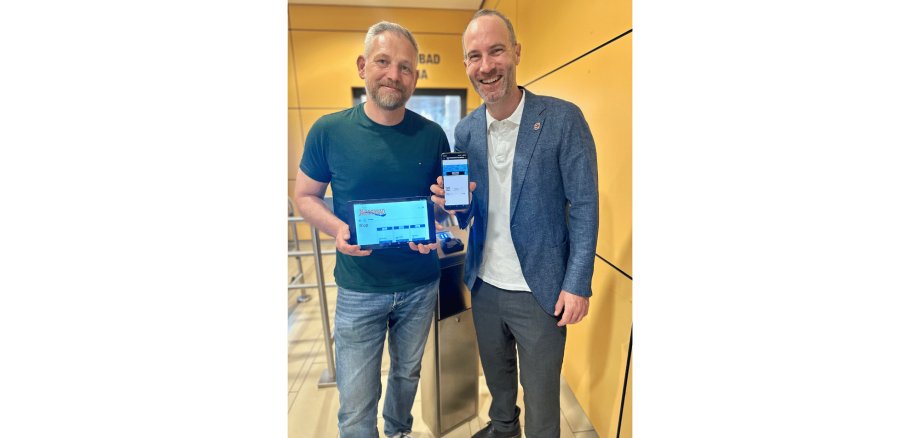 Zwei Männer stehend mit einem Tablet und einem Handy in der Hand