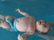 Baby liegt auf dem Rücken im Wasser